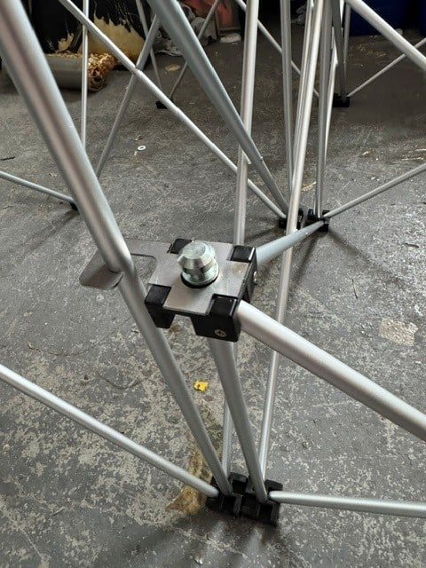 NexGen Riser Leg Link Clamp (Single) 6 Pack This spare parts connects riser legs together of different heights, for use with differing height riser legs where the deck platforms cannot be aligned. Such as a lower step or tier setup. Place the link clamp around the taller of the two riser legs, and over the Close-up of a metal scaffold joint with a bolt and clamp on a concrete floor coasted by cross braces and rails, mid-assembly piece.